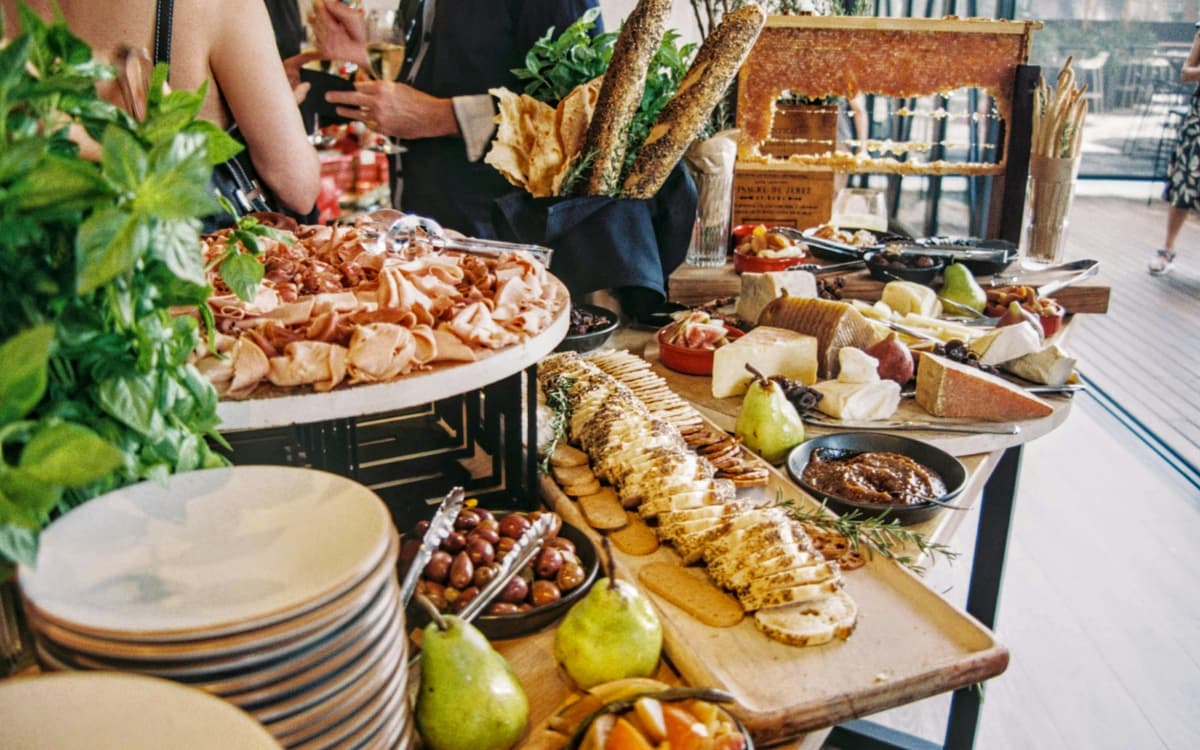 An event buffet with charcuterie boards, bread, fruit and stacked plates.